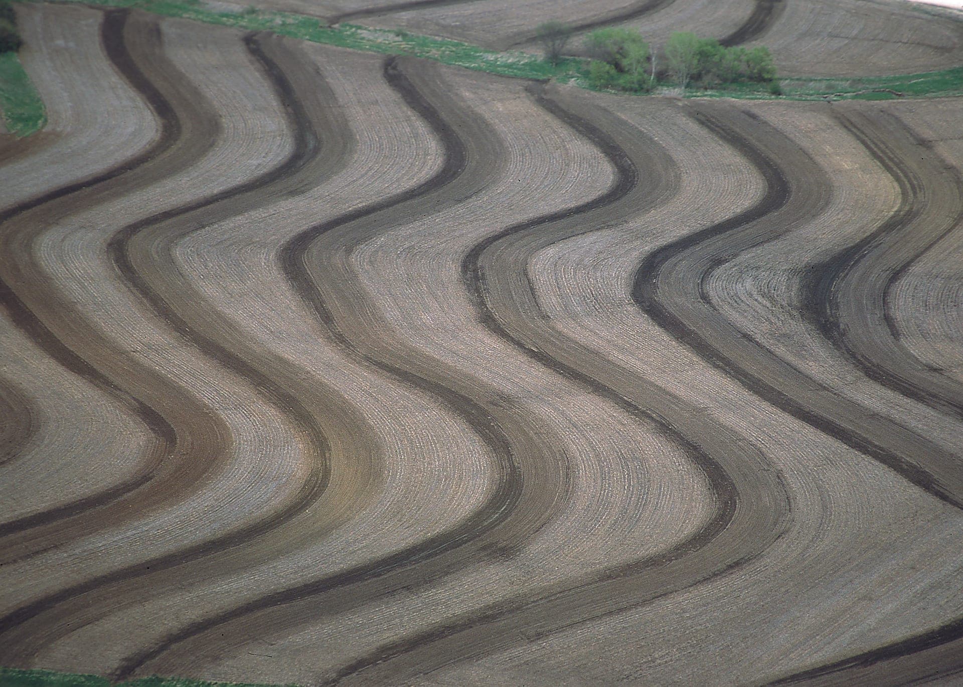 Aerial view of contour terraces on a Kansas field: parallel, wave-like bands traced across the worked soil.